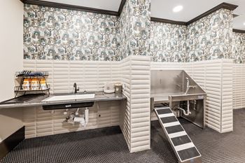 A kitchen with a sink, a stove, and a wallpapered wall.